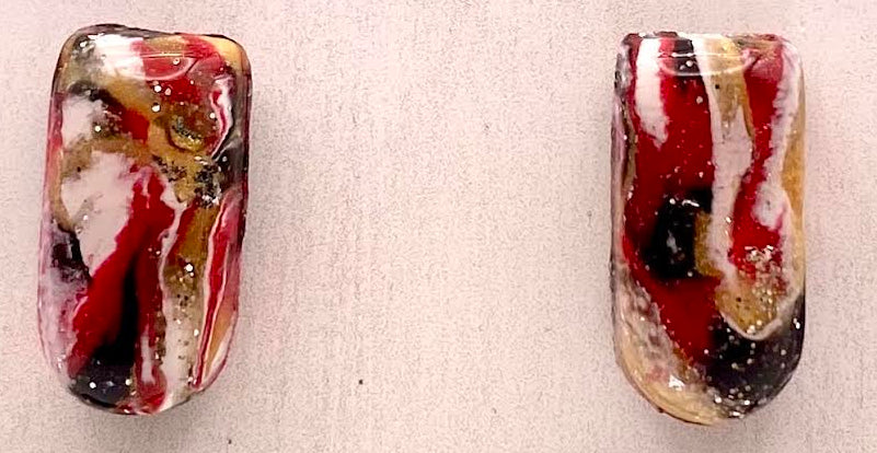 A pair of rectangular glass earrings with a marbled pattern of red, white, black, and gold, displayed on a light beige wooden card labeled 'Phoenix Frost Art'.