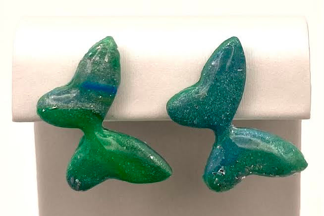 A pair of green butterfly-shaped stud earrings displayed on a white jewelry stand against a white background.