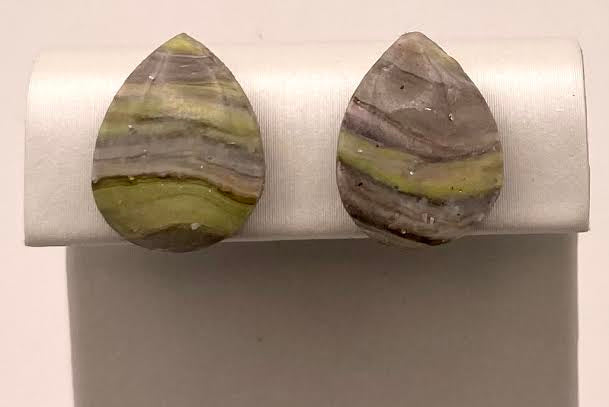 A pair of teardrop-shaped stud earrings with striped marbled stone in olive green, gray, and brown, displayed on a white jewelry stand against a light background.