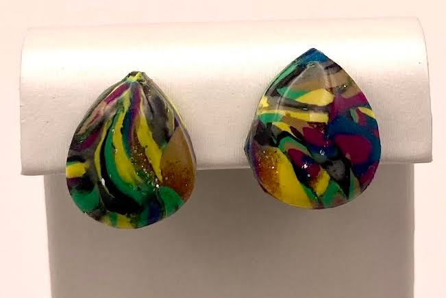A pair of teardrop-shaped stud earrings with a colorful marbled pattern in green, yellow, purple, and blue, displayed on a white jewelry stand.