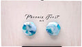 A pair of hexagon shaped earrings with a marbled blue, white, and light teal pattern, displayed on a light beige wooden card with the brand name 'Phoenix Frost Art' printed above them.