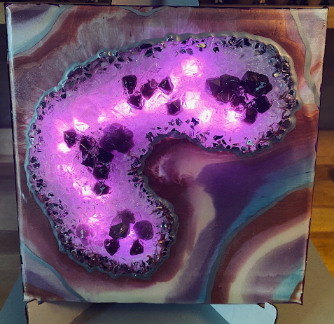A square canvas art print featuring a glowing purple and pink geode-like design with dark crystal shapes over a marbled agate-inspired background in purple, brown, and teal.