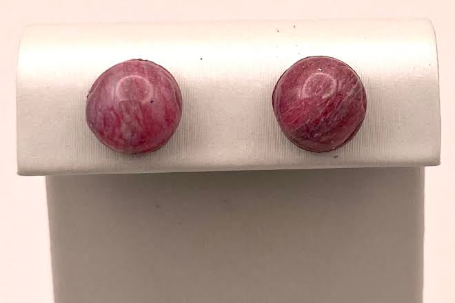 A pair of round stud earrings with marbled pink and purple stone, displayed on a white rectangular jewelry stand against a light background.