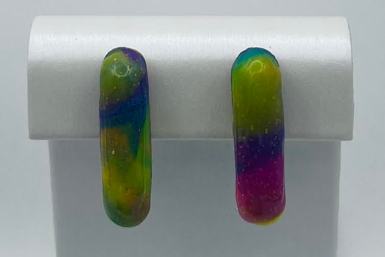 A pair of colorful marbled glass drop earrings displayed on a white rectangular stand against a light gray background.