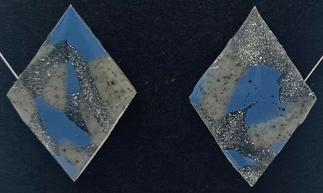 Diamond-shaped resin earrings with a blue, gray, and white marbled pattern, displayed on a black backing card with 'Phoenix Frost Art' and 'Handmade' written in white script.