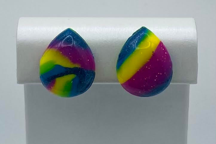 A pair of teardrop-shaped stud earrings with a marbled rainbow pattern of blue, green, yellow, and purple, displayed on a white jewelry stand.